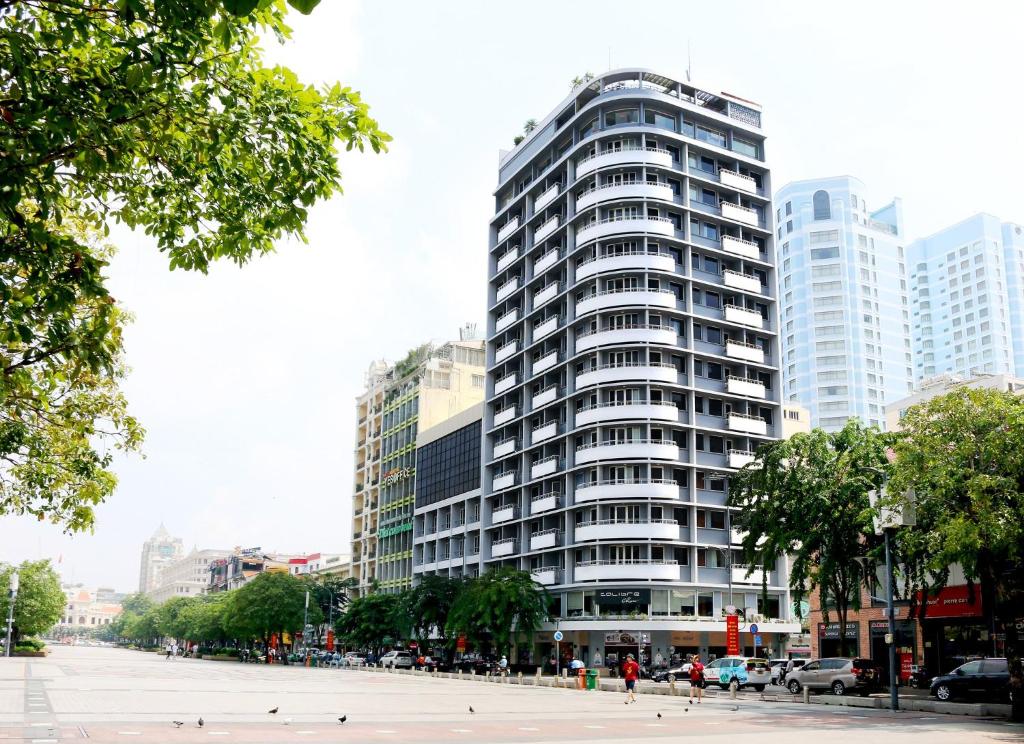 a tall building with people walking in front of it at Palace Hotel Saigon in Ho Chi Minh City