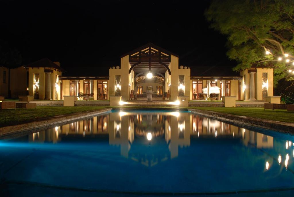 a villa with a swimming pool at night at Dawsons Game Lodge in Badplaas