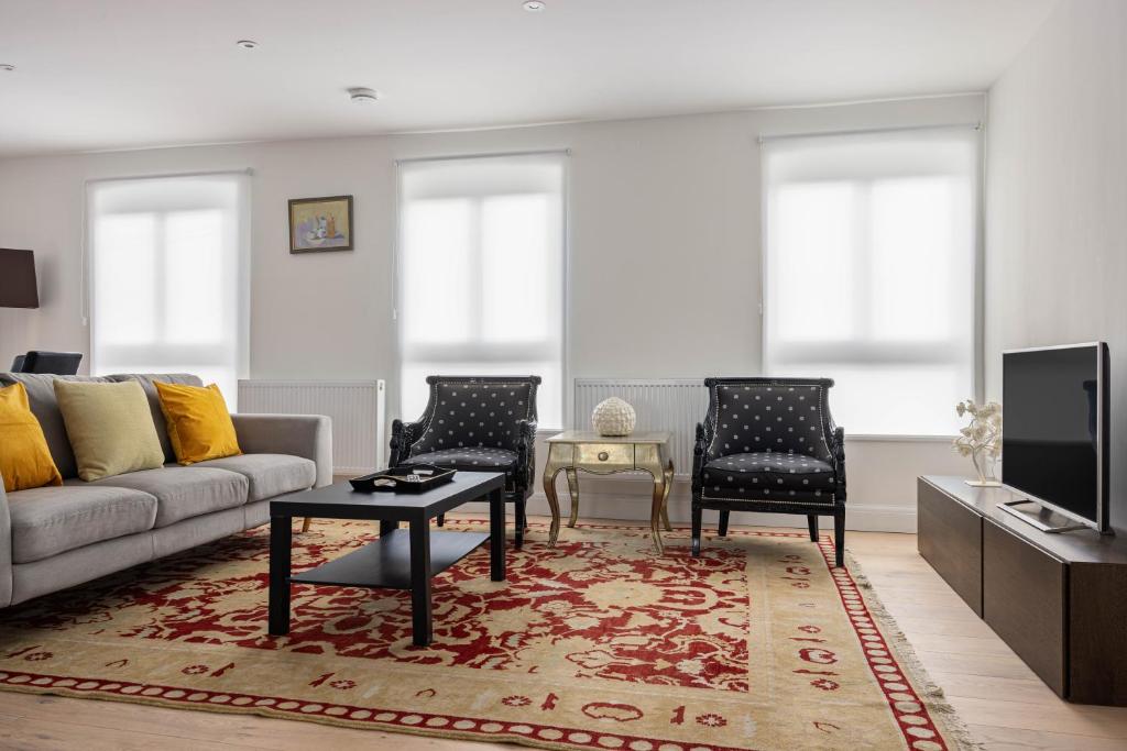 sala de estar con sofá y 2 sillas en Kensington High Street Apartments en Londres