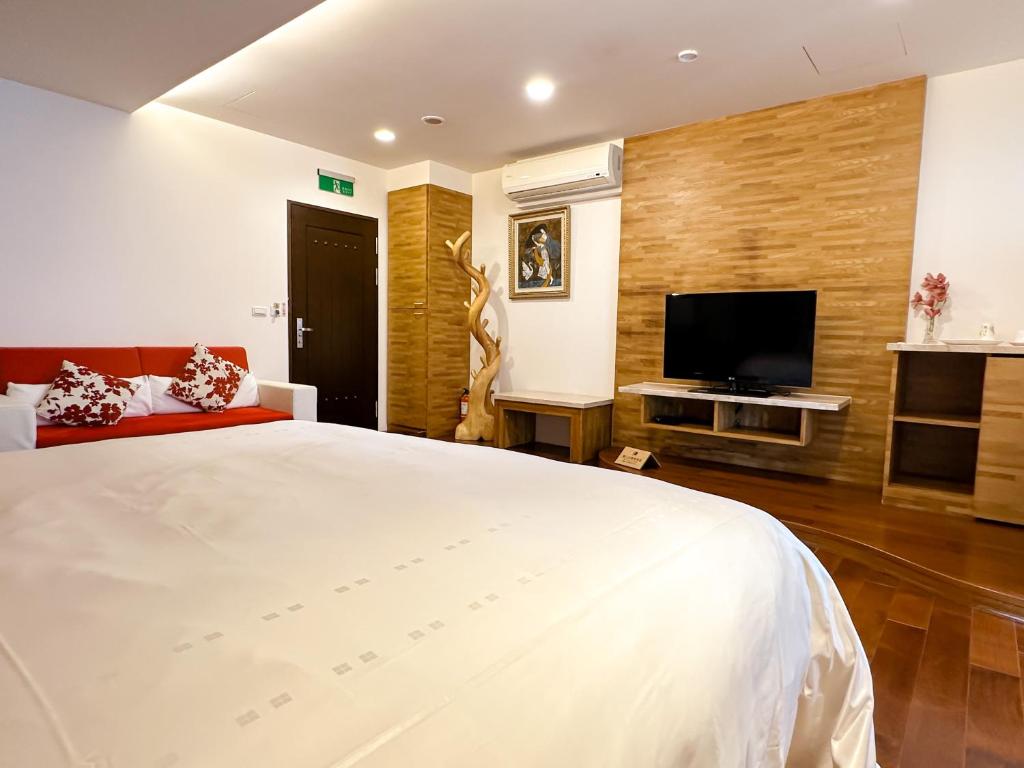 a bedroom with a large white bed and a flat screen tv at Yage Hotspring House in Jiaoxi