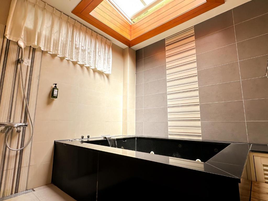 a bathroom with a large bath tub with a skylight at Yage Hotspring House in Jiaoxi