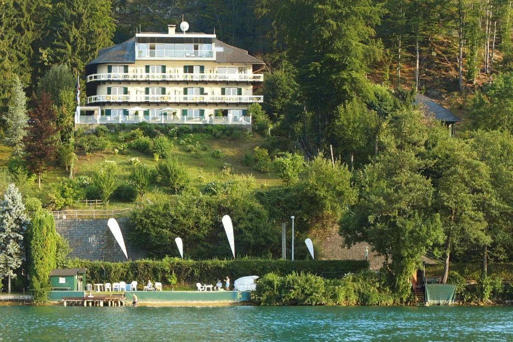 a large building sitting on top of a hill next to a lake at Holiday flats Seehaus Gaby Maria Wörth am Wörthersee - OKT01013-SYC in Reifnitz
