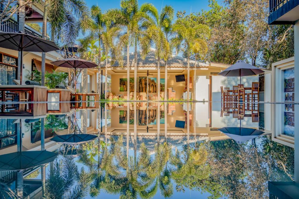 um reflexo de uma casa com palmeiras na água em Amatak Boutique Hotel em Siem Reap