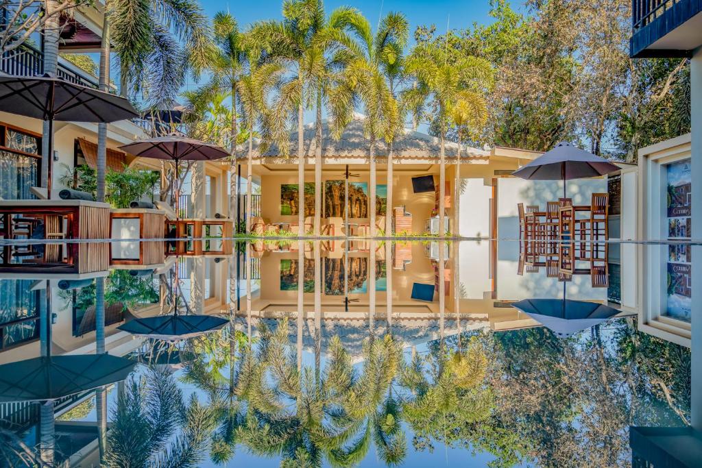a reflection of a house with palm trees in the water at Amatak Boutique Hotel in Siem Reap
