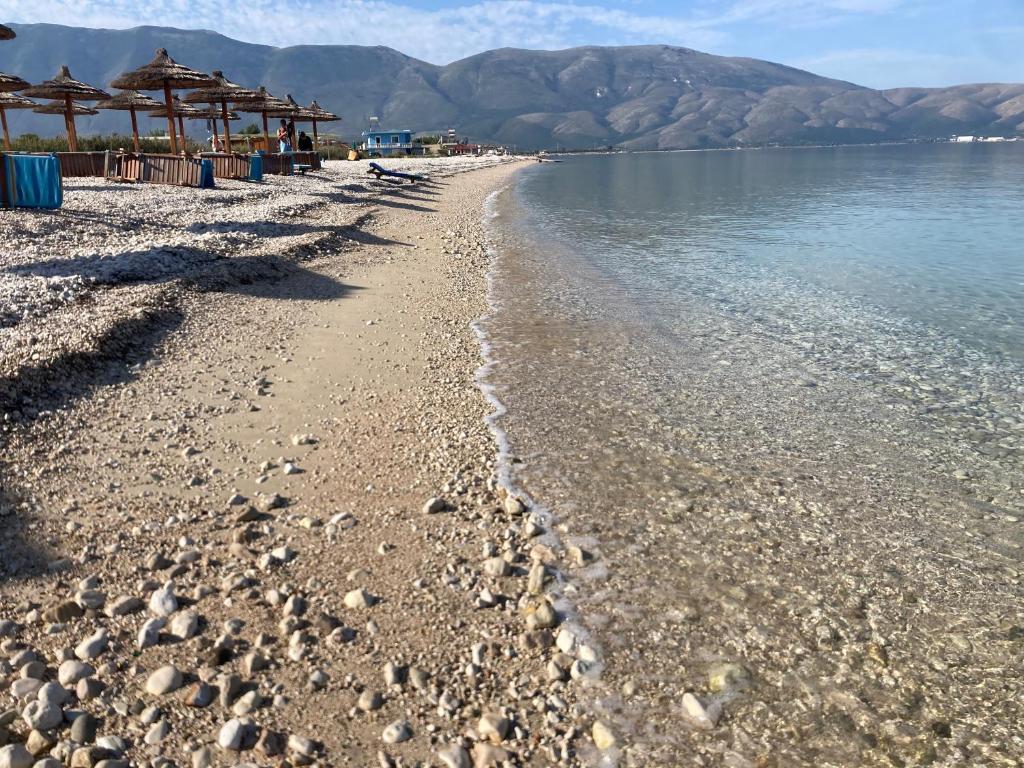 a beach with rocks and umbrellas and the water at Blue Paradise Hotel in Orikum