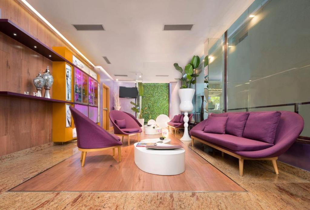 una sala de estar con sillas moradas y un sofá púrpura. en NH Ourense, en Ourense