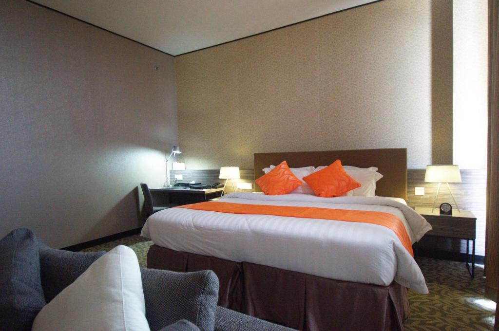 a hotel room with a large bed with orange pillows at Grand Alora Hotel in Alor Setar