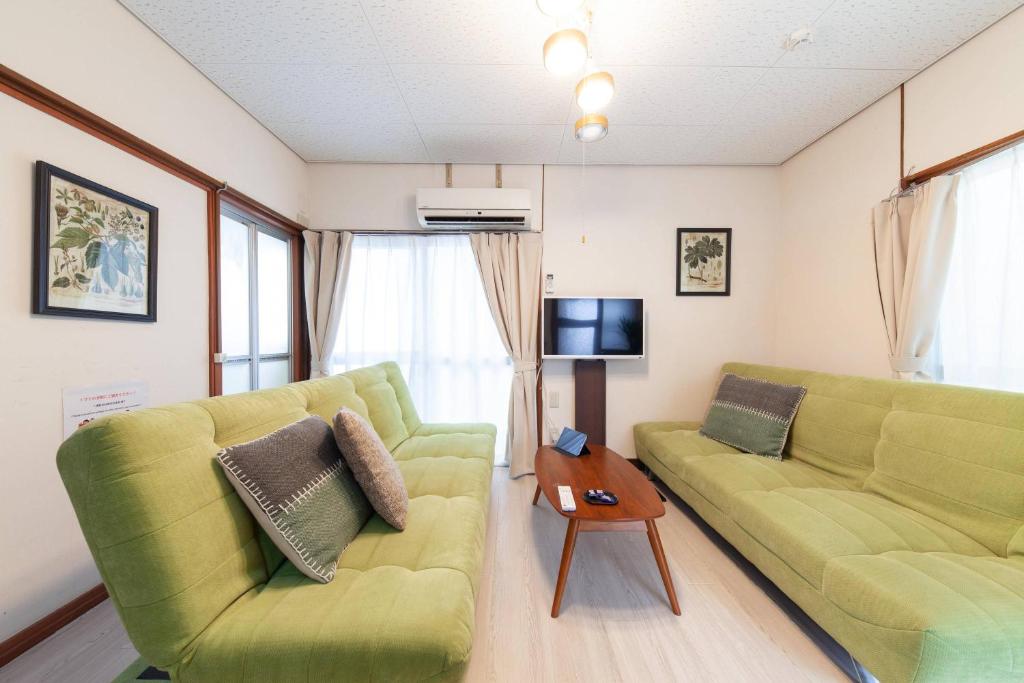 a living room with two green couches and a table at Honmachi House in Tokyo