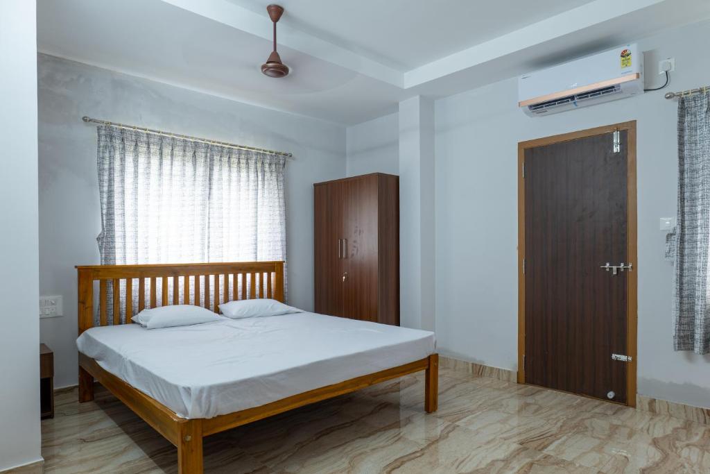 1 dormitorio con 1 cama y puerta de madera en Rashra Residency en Manipala