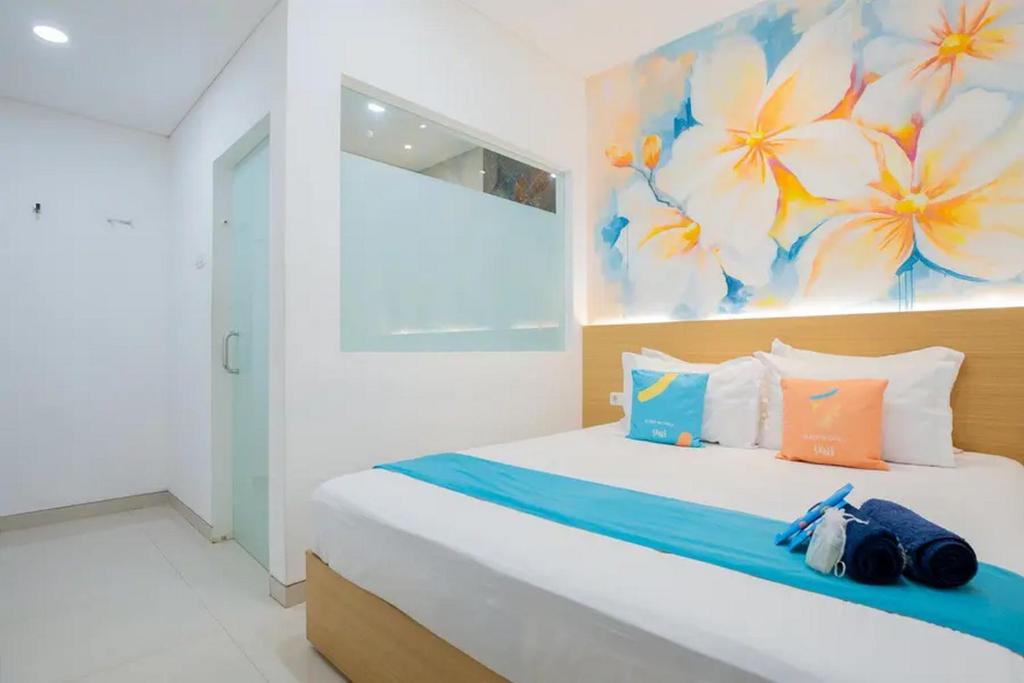 a bedroom with a bed with a painting on the wall at Sans Hotel Box Mansion Surabaya by RedDoorz in Wonokitri 2