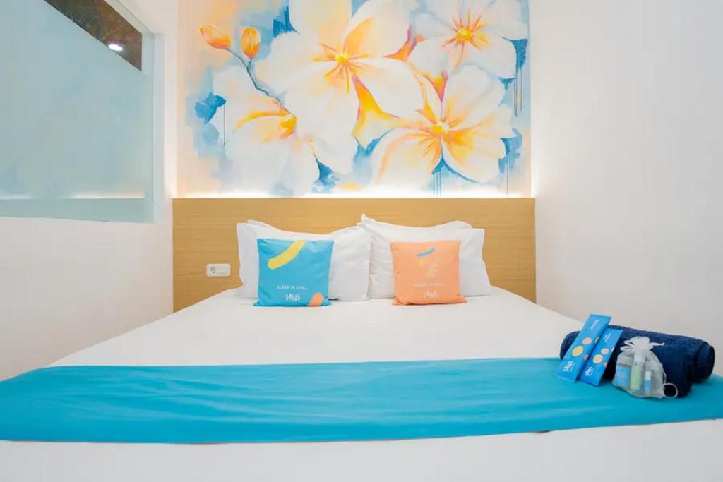 - une chambre avec un lit doté d'oreillers bleus et oranges dans l'établissement Sans Hotel Box Mansion Surabaya by RedDoorz, à Wonokitri 2