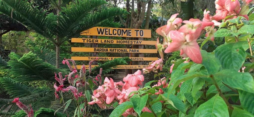 Tiger Land Homestay في Bhurkīā: علامة في وسط حديقة بها زهور وردية