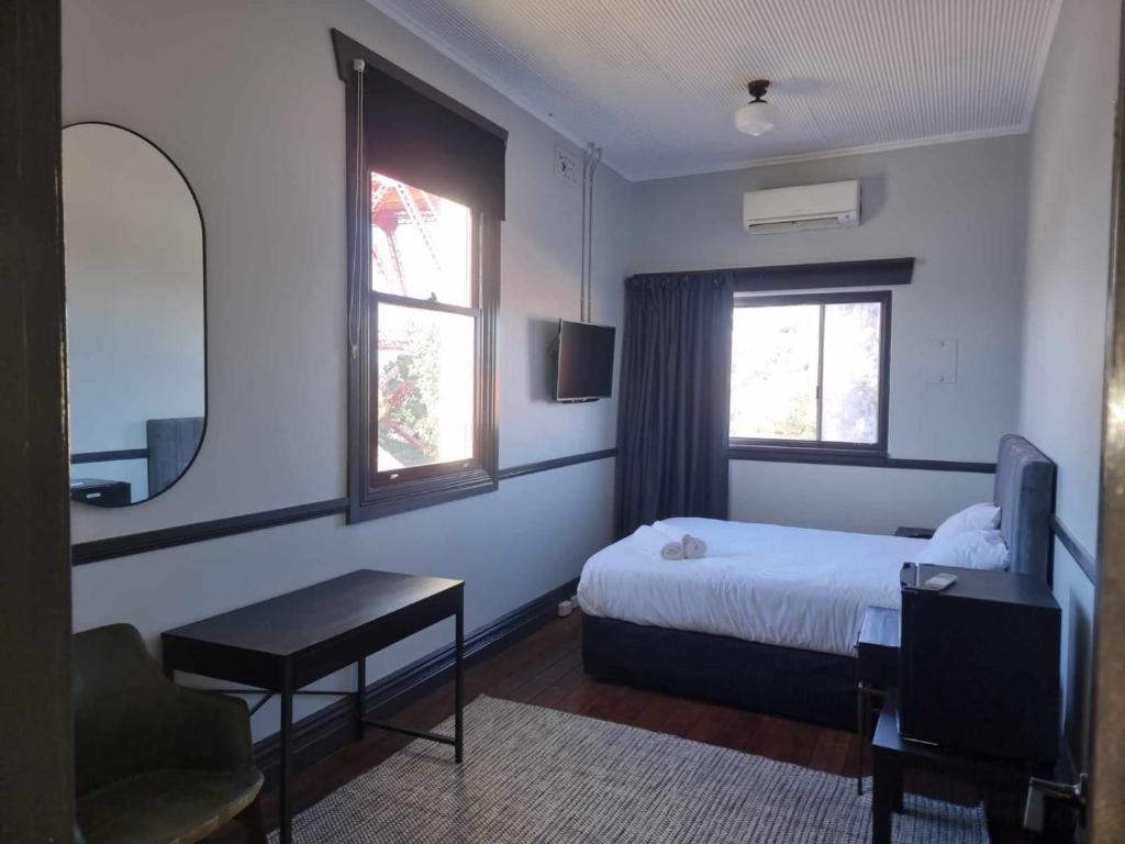 1 dormitorio con cama, escritorio y ventana en The Federal Hotel, en Kalgoorlie