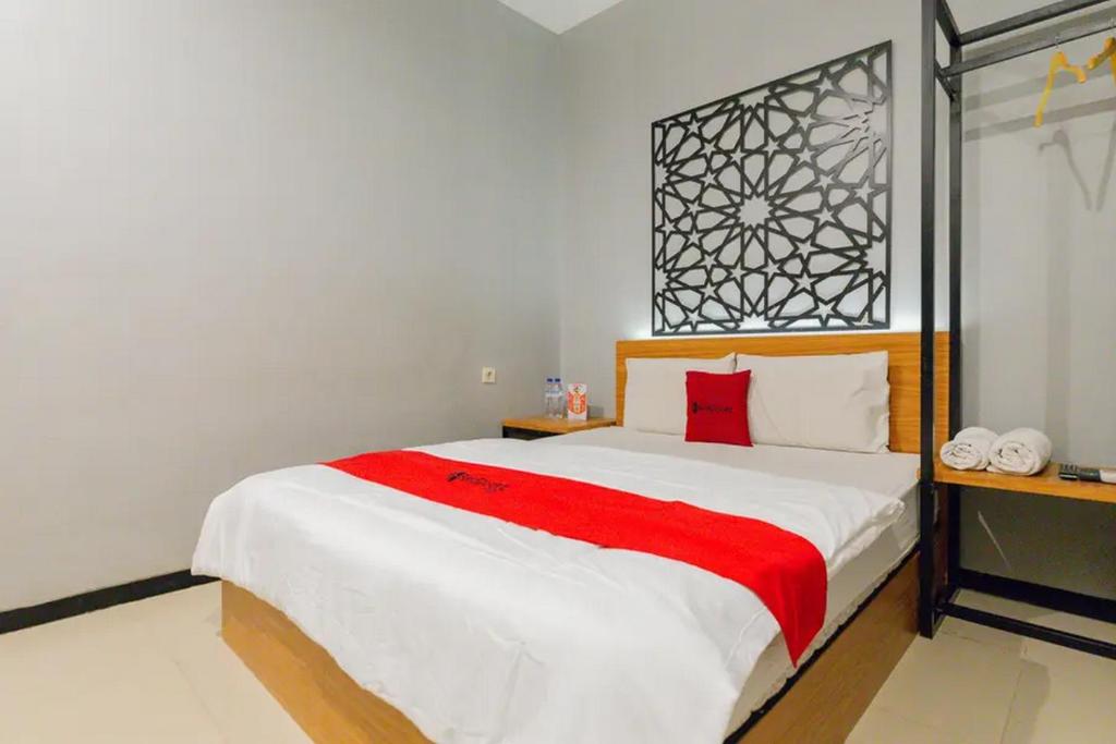 een slaapkamer met een groot bed en een rode deken bij RedDoorz @ Manukan Surabaya in Surabaya