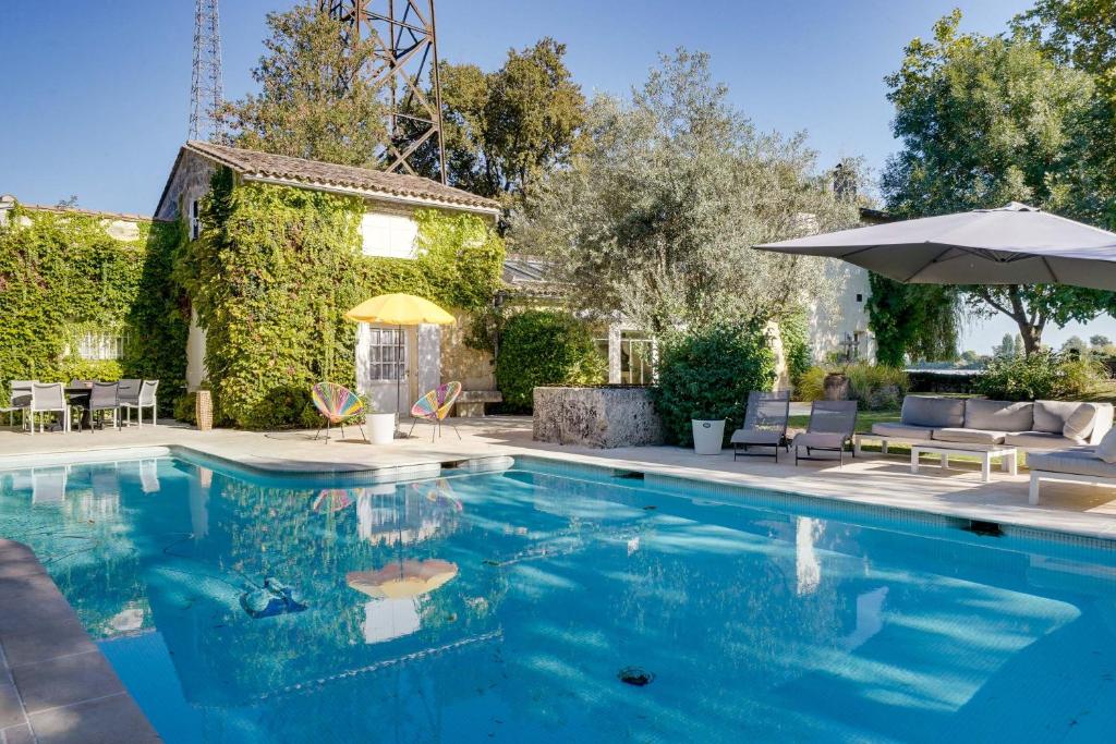 une piscine avec des chaises et un parasol dans l'établissement LA DEMEURE - Incroyable maison en bord de Dordogne, à Saint-Loubès