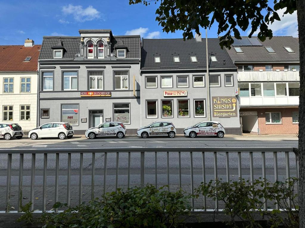 un edificio con varios coches estacionados frente a él en Hotel Deutscher Hof, en Schleswig