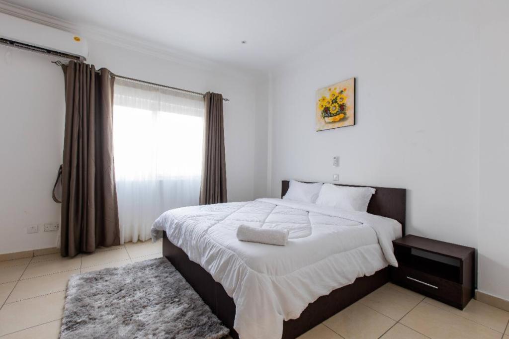 um quarto com uma cama grande e uma janela em HOLI FLATS em Accra