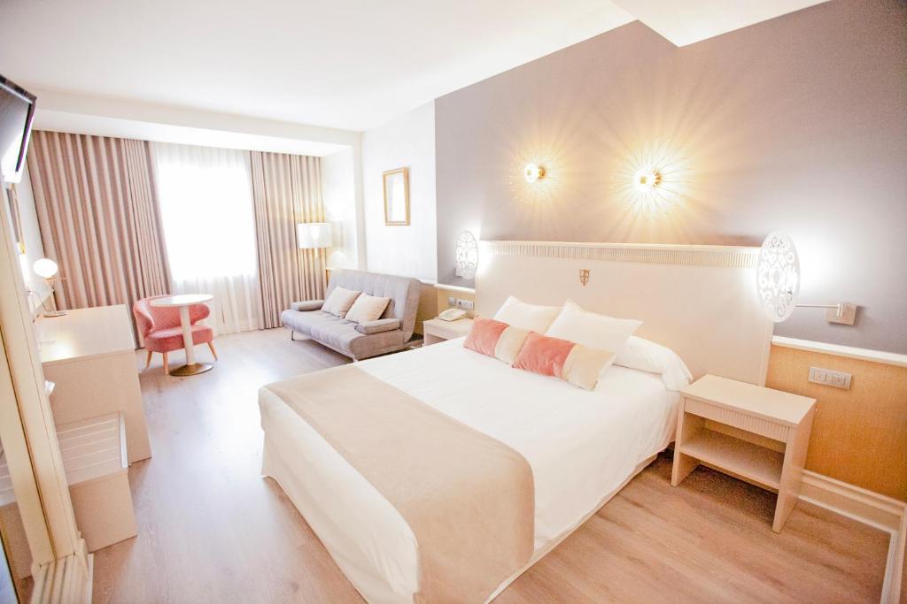 a hotel room with a large white bed and a chair at Hotel Alfonso VIII in Soria