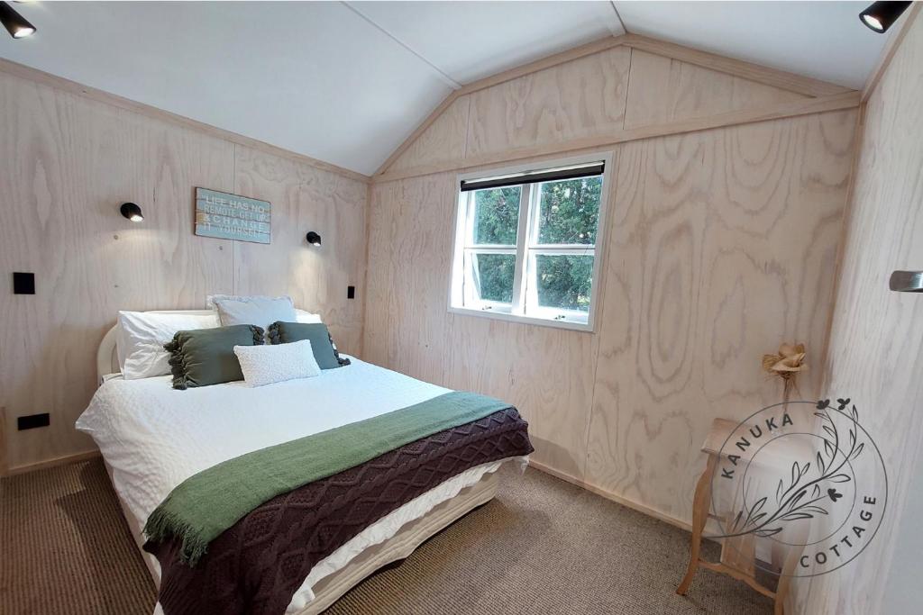 a bedroom with a bed and a window at Kanuka Cottage in Whitianga