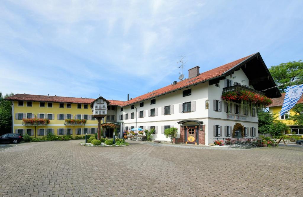 un grand bâtiment blanc avec un toit rouge dans l'établissement Hotel Neuwirt, à Sauerlach