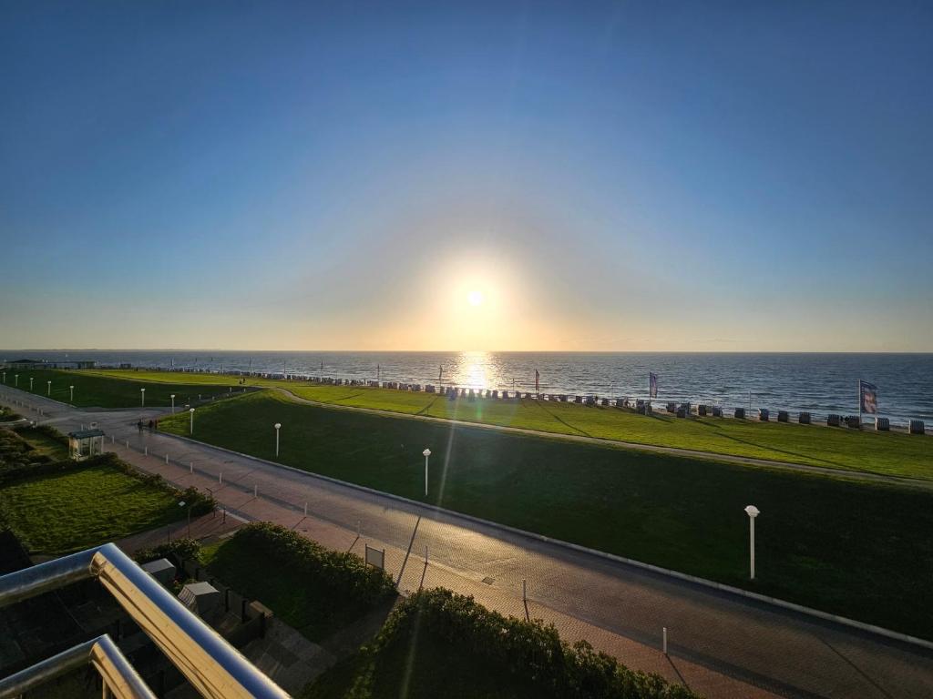 a view of the ocean with the sun in the sky at Kaiserhof 31 mit Meerblick - Reinke in Norderney