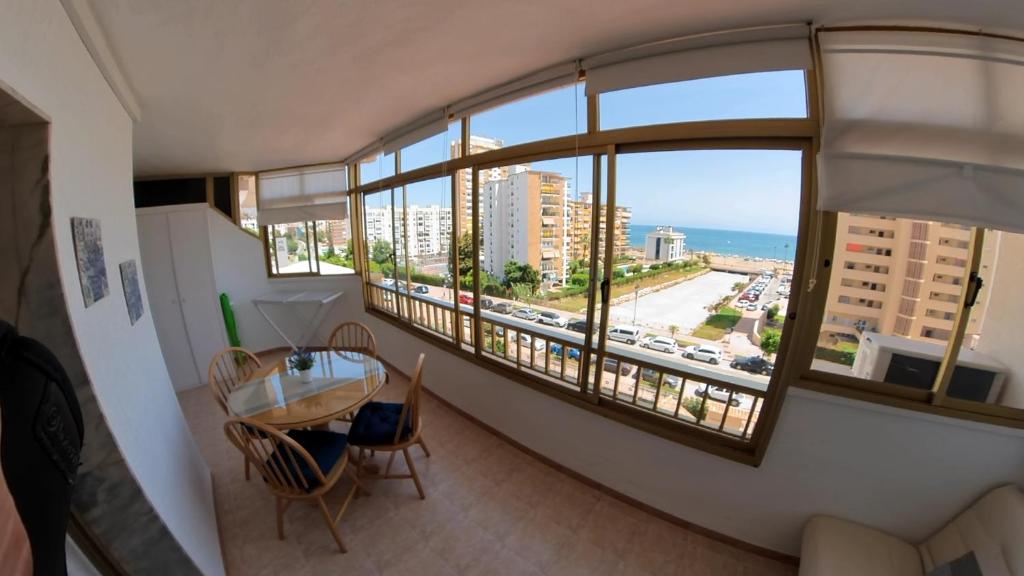 a room with a table and chairs and a large window at Poseidón Apartamento frente a la playa in Fuengirola