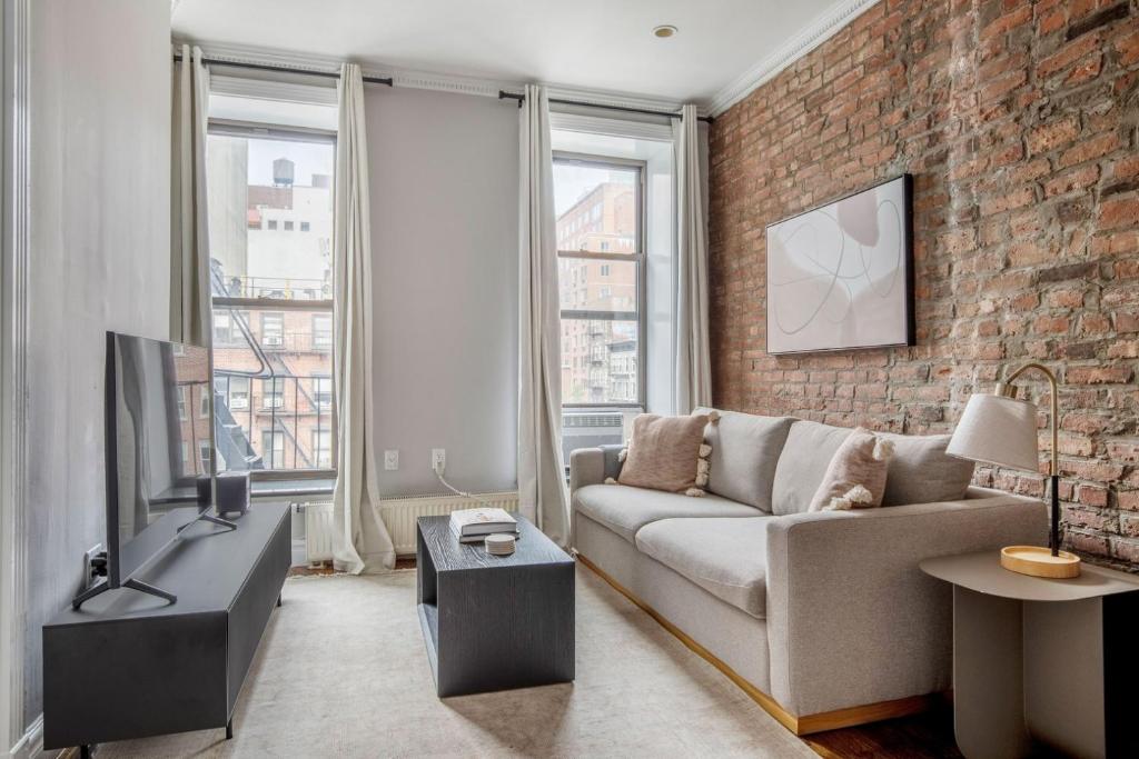 a living room with a couch and a brick wall at East Village 2br w wd nr groceries NYC-1221 in New York