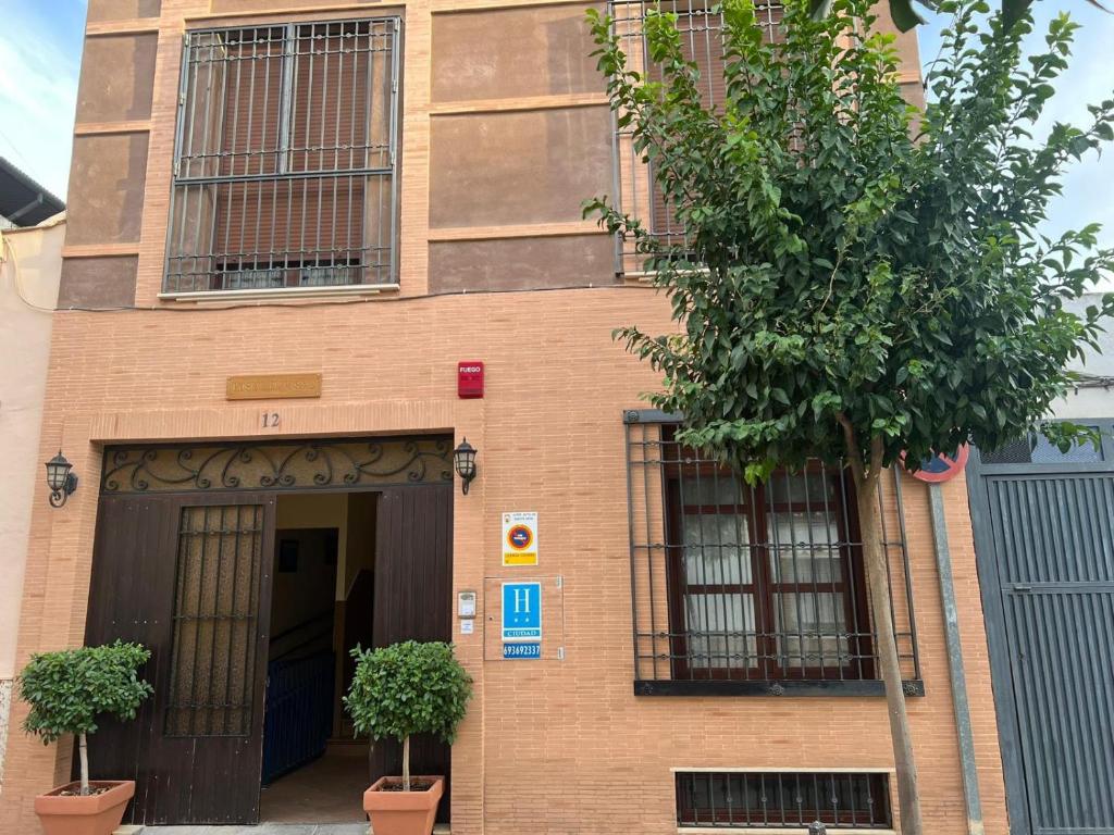 a brick building with two windows and a door at Hostal el Pasaje in Puente Genil