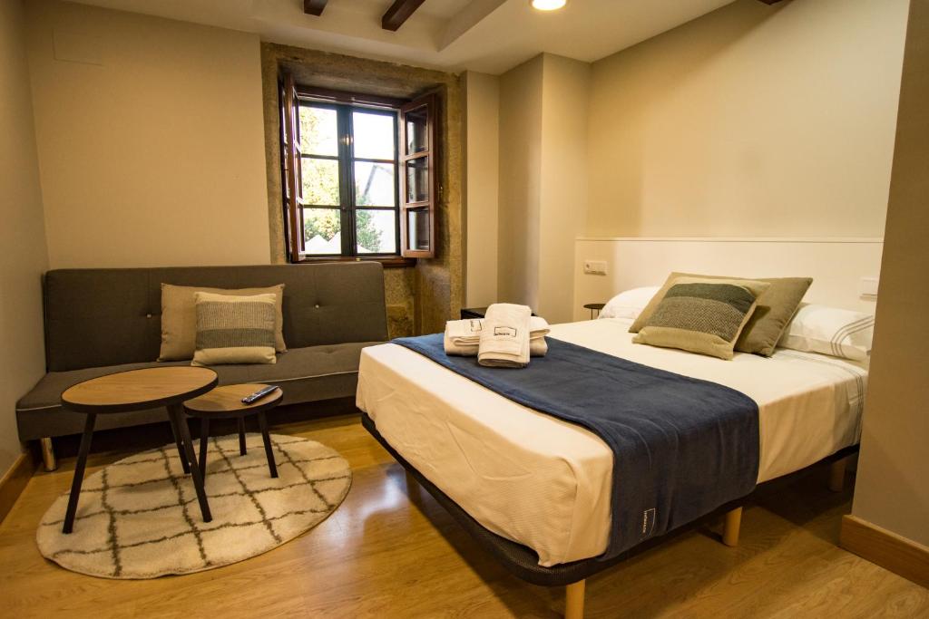 a bedroom with a large bed and a table at hostal Nomade Santiago in Santiago de Compostela