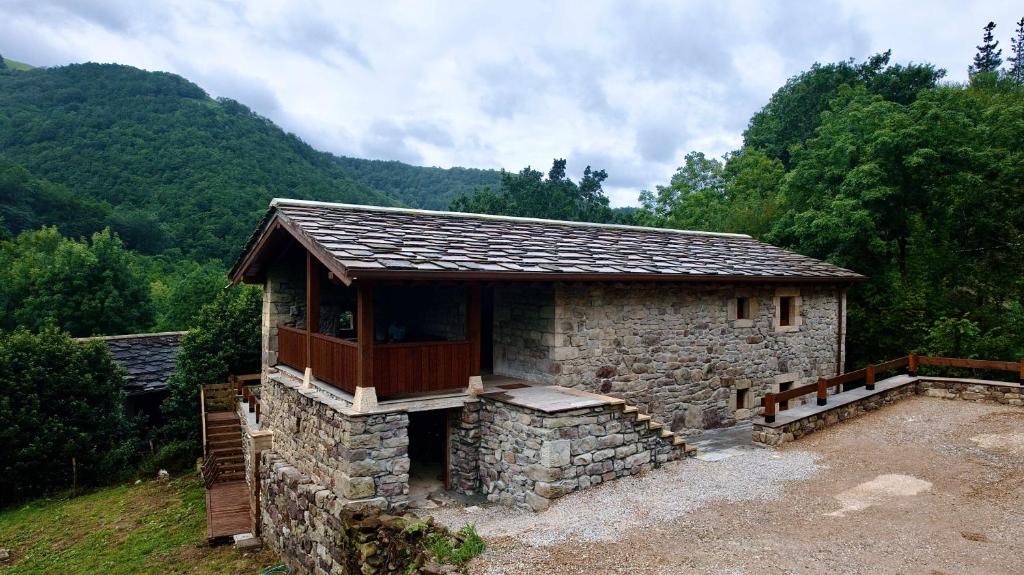 un pequeño edificio de piedra con balcón en una colina en Cabaña Pasiega Castro Valnera, en Vega de Pas