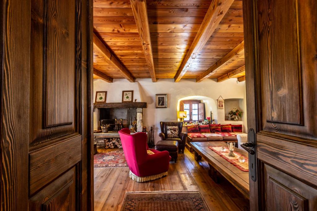 una sala de estar con techos de madera y una silla roja. en L'Atelier du Temps - LE SECRET, en Aosta