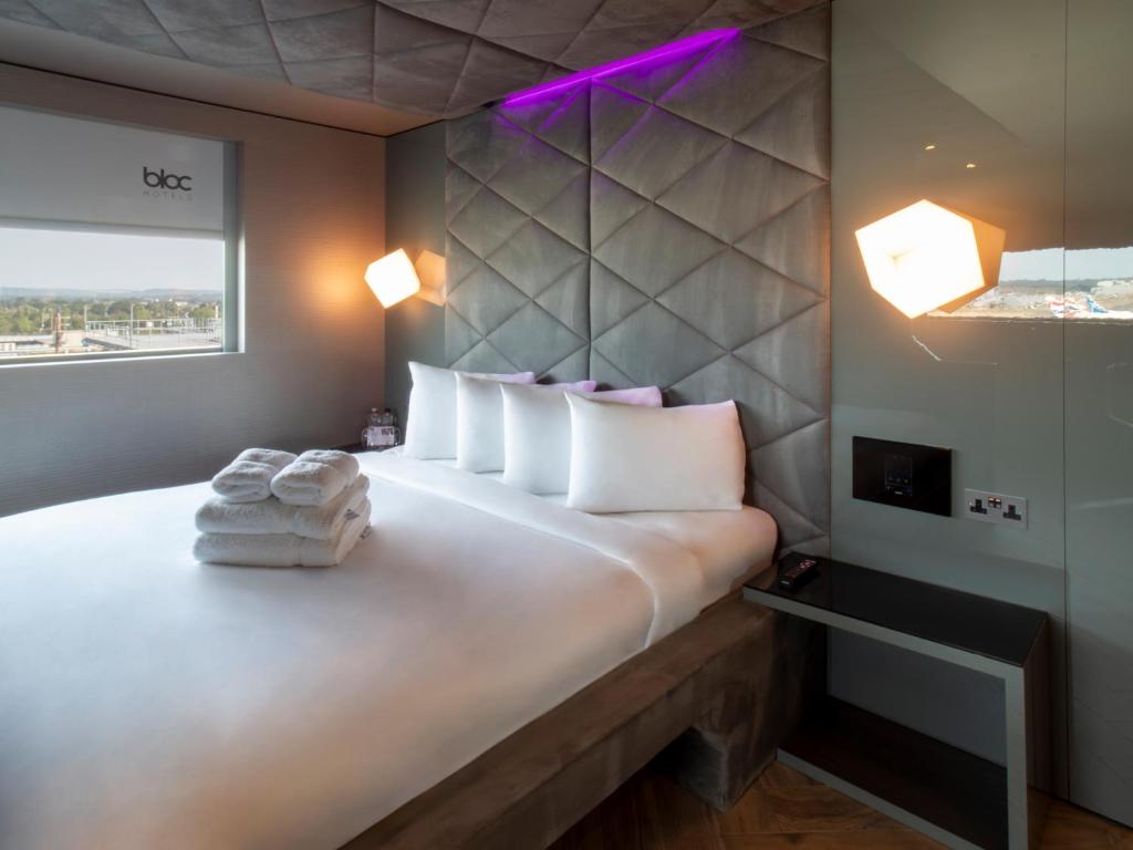 1 dormitorio con 1 cama grande con almohadas blancas en Bloc Hotel London Gatwick Airport, en Horley