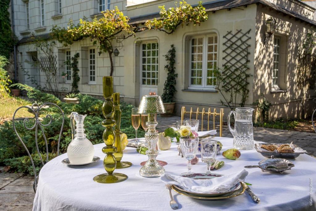 a table with a white table cloth and vases on it at Chambres d'Hôtes Manoir de Montecler in Chènehutte-les-Tuffeaux
