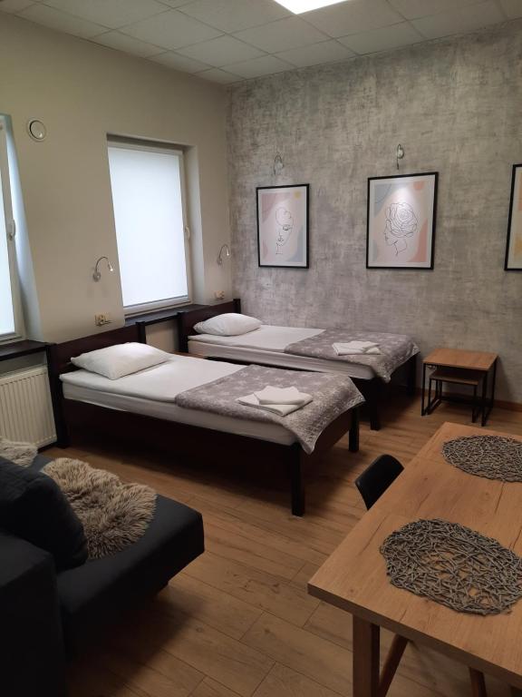 pokój z 3 łóżkami i stołem w obiekcie Hotelik Corner w mieście Kętrzyn