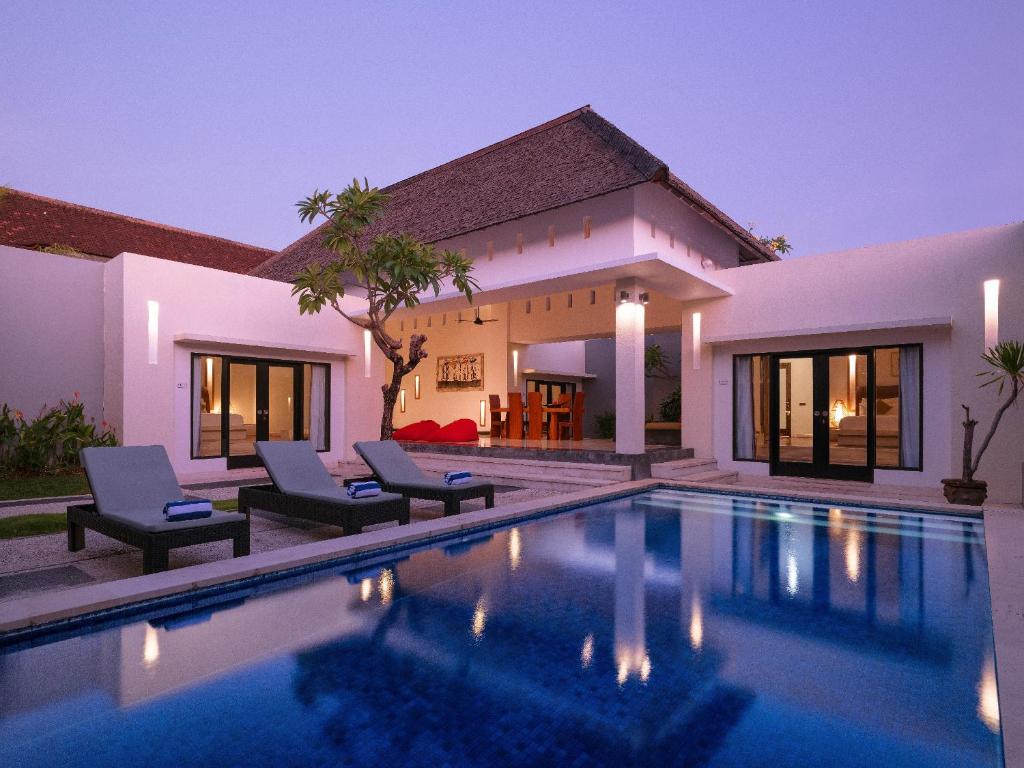 a villa with a swimming pool at night at The Seminyak Suite - Private Villa in Seminyak