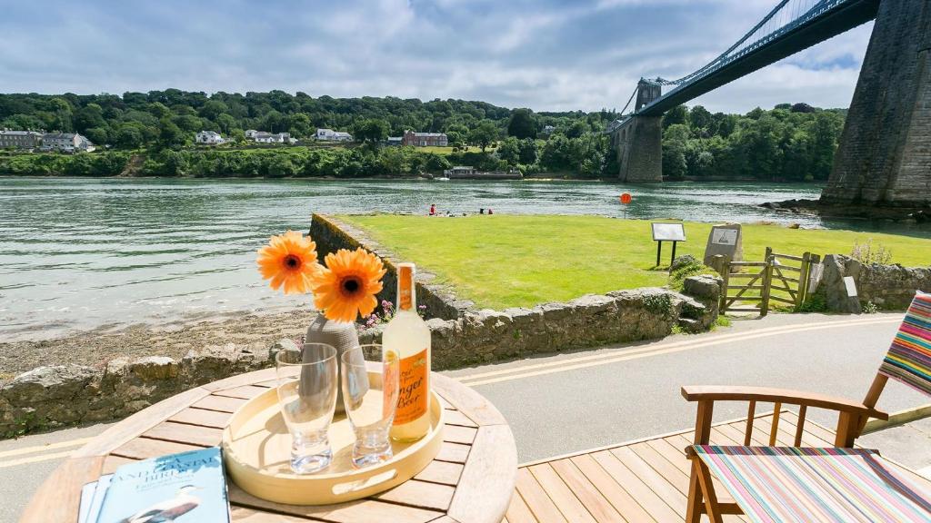 a table with a bottle of wine and flowers on it at Noddfa in Menai Bridge