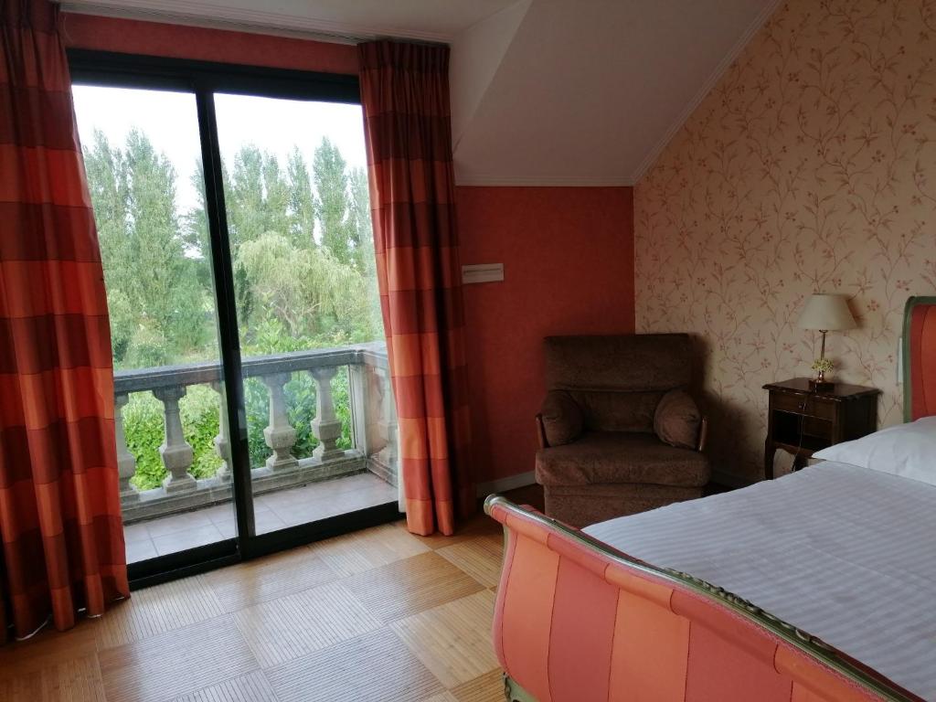 ein Schlafzimmer mit einem Bett, einem Stuhl und einem Fenster in der Unterkunft Les Résidences du Moulin in Téteghem
