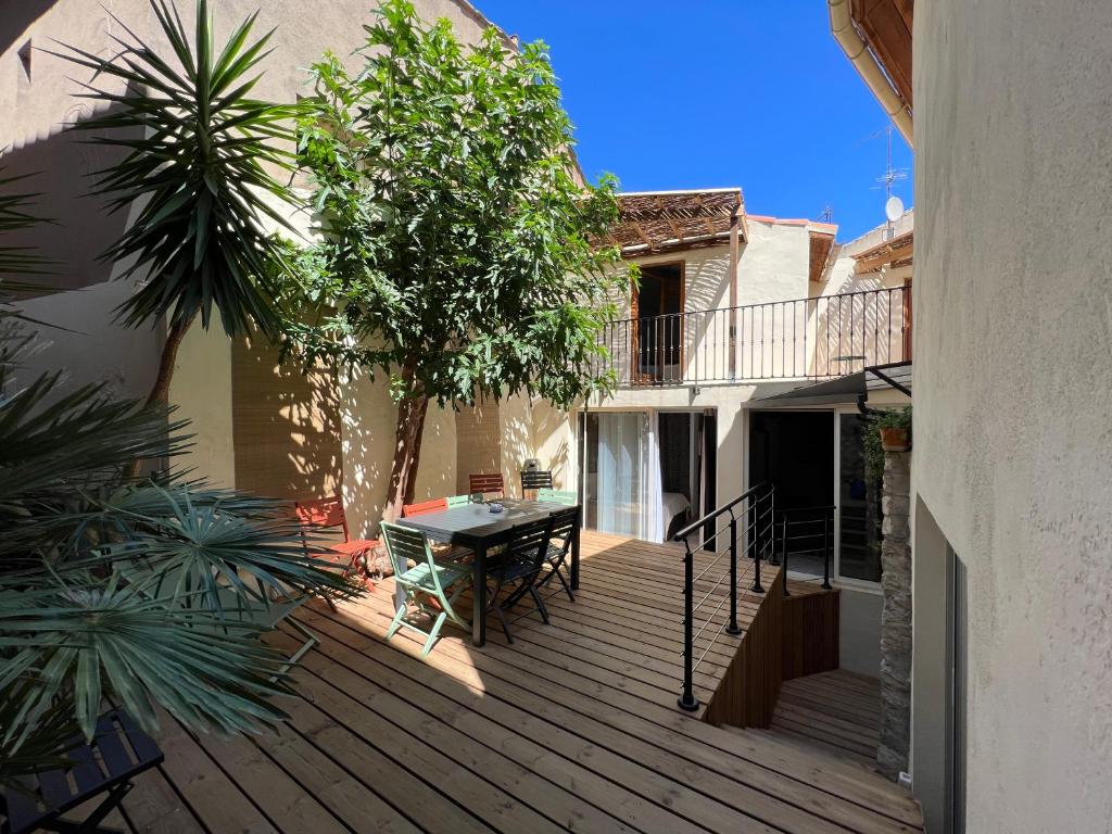 une terrasse en bois avec une table et un arbre dans l'établissement Maison T4 centre ville et plage, à Balaruc-les-Bains