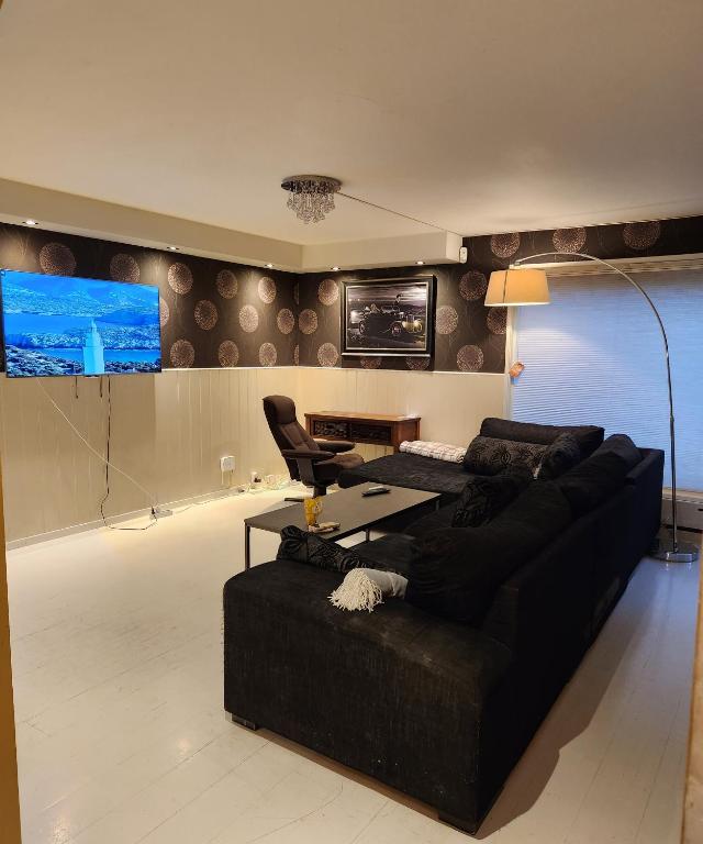 a living room with a black couch and a desk at Aparthouse OSLO in Oslo