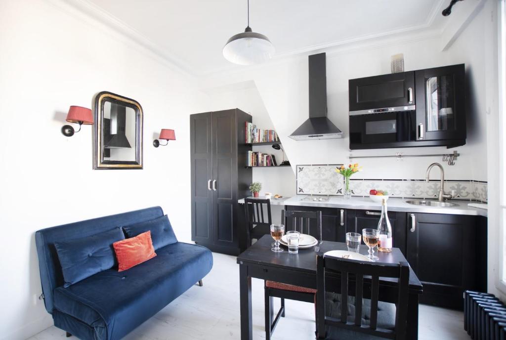 un salon avec un canapé bleu et une table dans l'établissement GuestReady - 2 pièces lumineux vue sur Notre Dame, à Paris