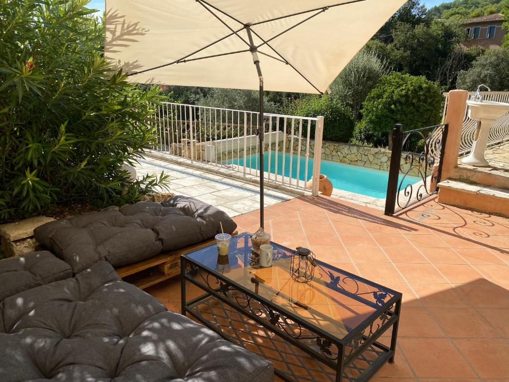 eine Terrasse mit einem Tisch und einem Sonnenschirm neben einem Pool in der Unterkunft La maison Provençale in Cotignac