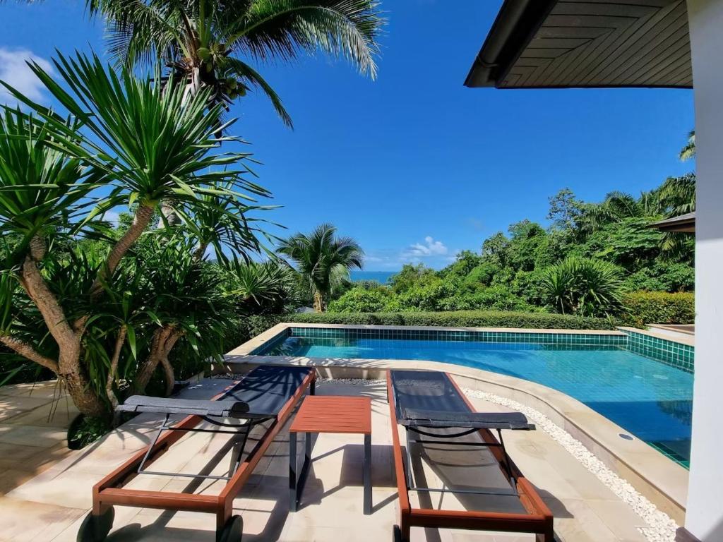 een resort met een zwembad, stoelen en palmbomen bij Baan Phukhao in Klong Muang Beach