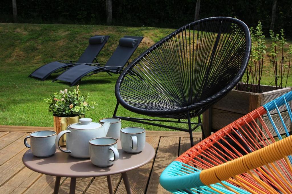 a table with cups and a chair on a patio at Maison Mélèry in Saint-Pierre-du-Val