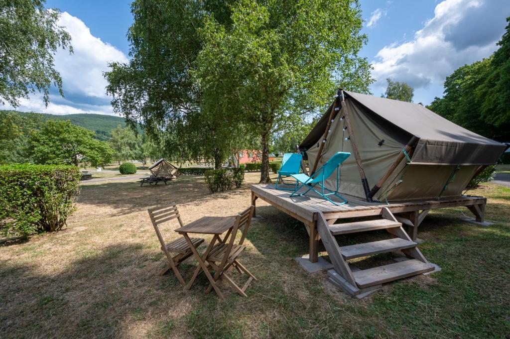 a tent and two chairs and a table and a bench at Camping Les Vosges du Nord in Oberbronn
