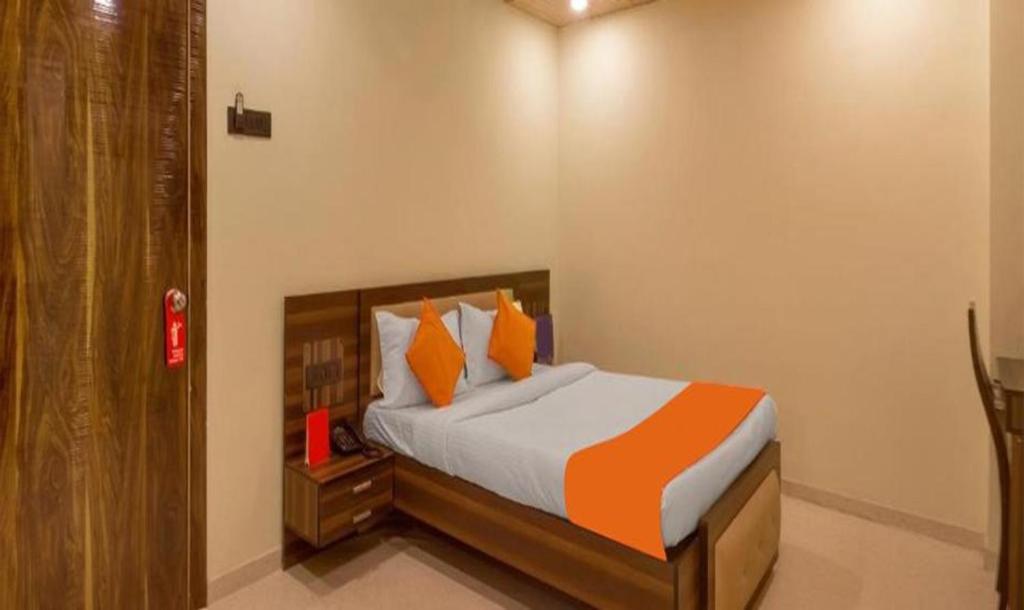 a bedroom with a bed with orange pillows at FabHotel Gargi Suites Shivajinagar in Pune