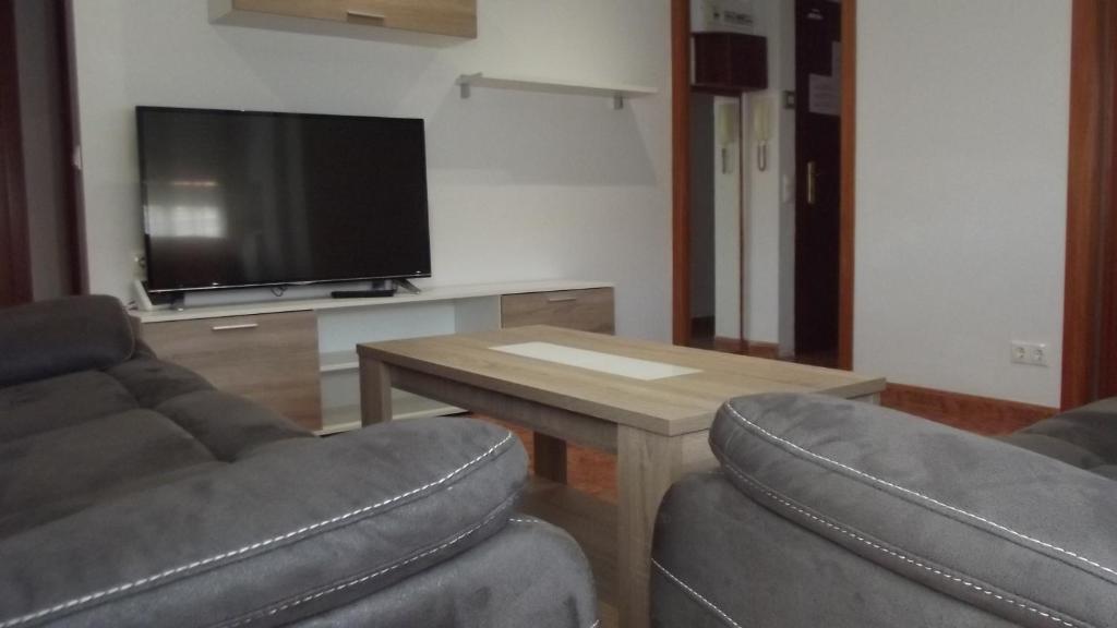 sala de estar con 2 sillas, mesa y TV en Apartamentos Atlas Terrassa I, en Terrassa