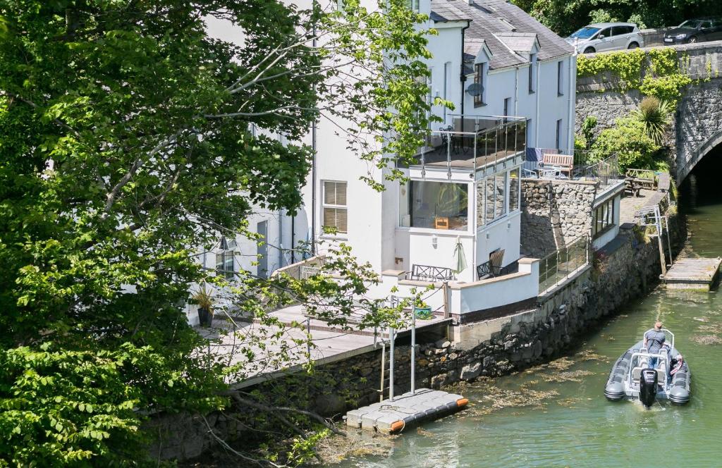 a house on the side of a river with a boat at The Moorings in Menai Bridge