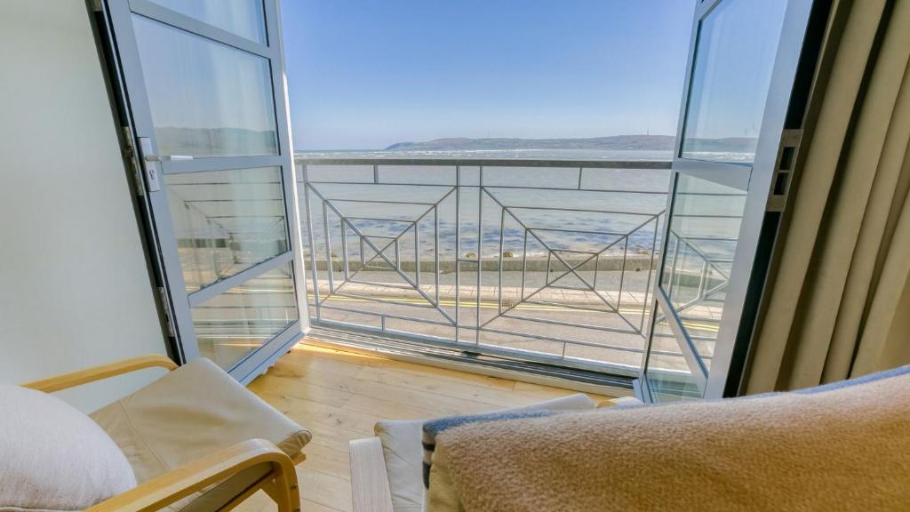 a room with a balcony with a view of the ocean at The Quay in Benllech