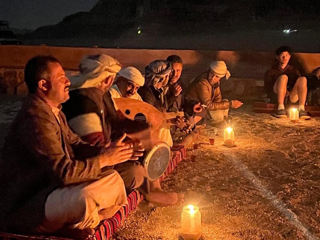 um grupo de pessoas sentadas à volta de uma fogueira com velas em Bedouin Traditions Camp em Wadi Rum