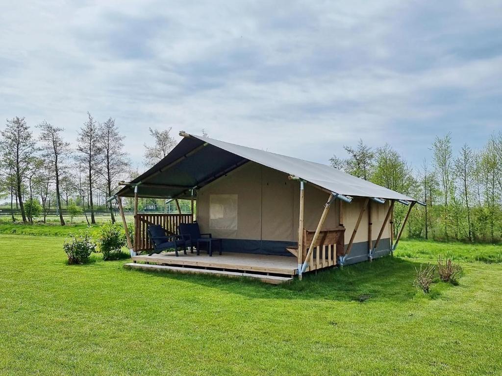 une grande tente dans un champ d'herbe dans l'établissement Luxury glamping with private bathroom near the Frisian waters, à De Veenhoop
